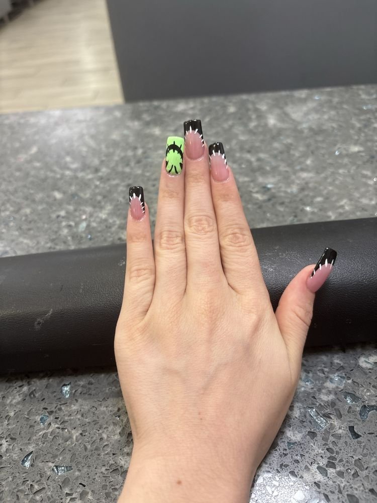 Long square nails with black stitched French tips and a lime green accent nail